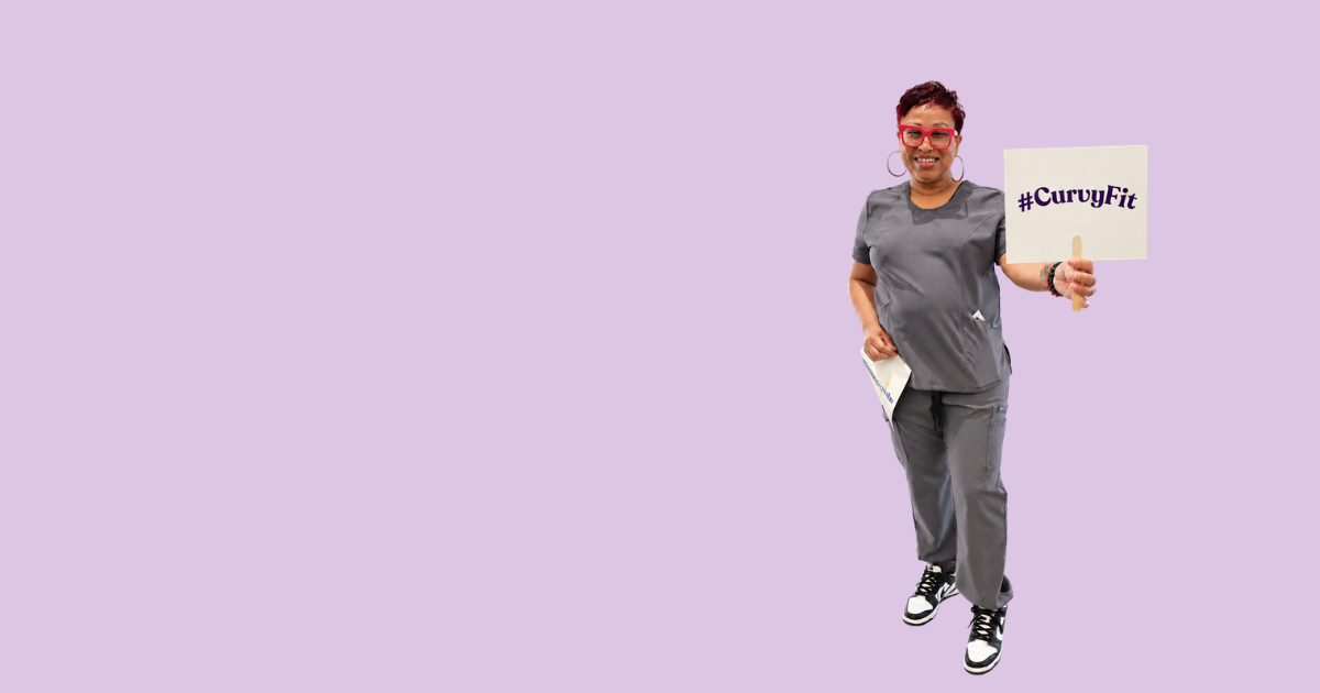 Woman smiling and wearing grey scrubs. She is holding a sign that says #curvyfit
