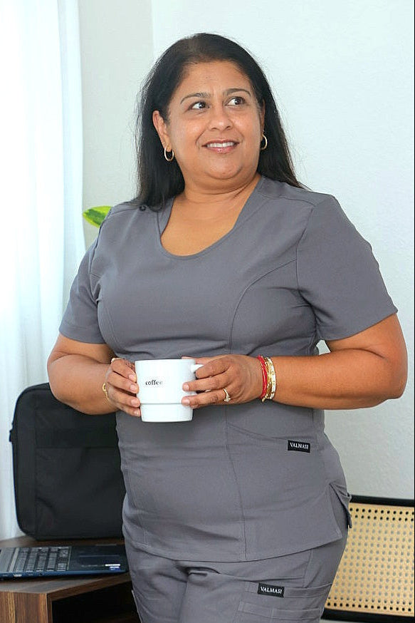Healthcare professional wearing grey Valmasi scrub top in a modern medical environment, showcasing durability and ease.