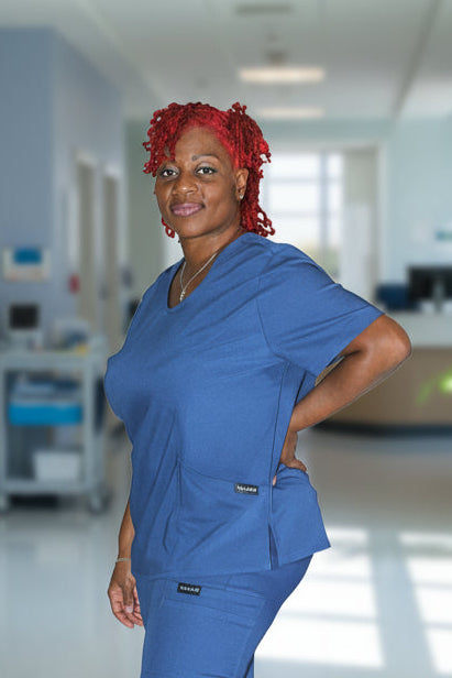 Blue scrub top with two front pockets and curved seams for a flattering fit.