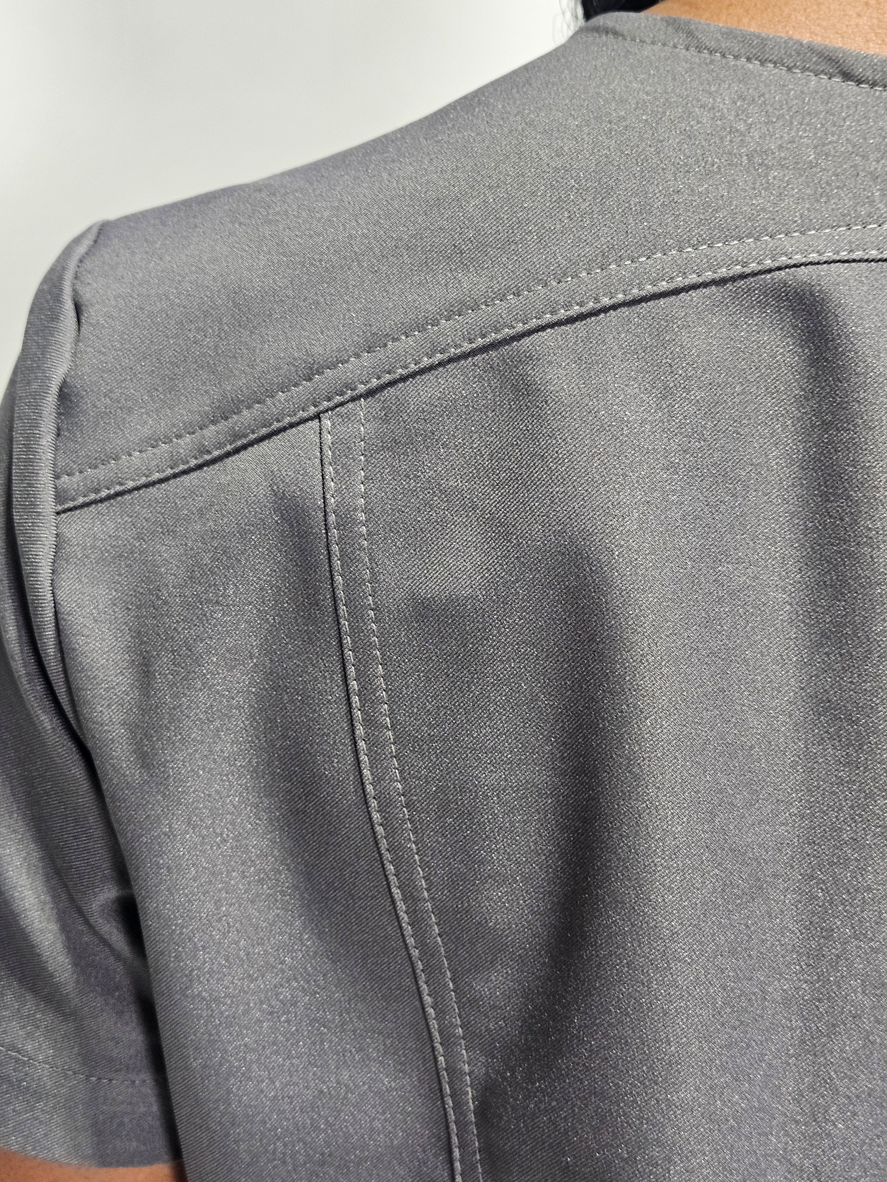 Lightweight grey scrub top with soft stretch material, curved seams, and utility pockets.