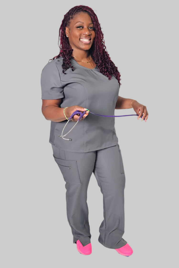 Woman wearing grey scrubs holding a stethescope.